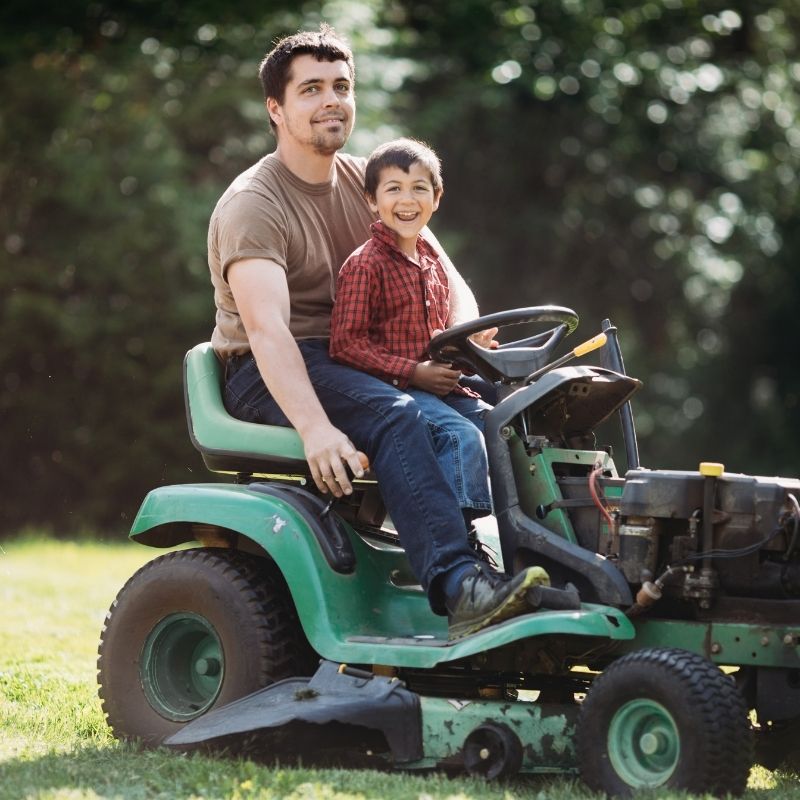 Father and son on riding lawn mower